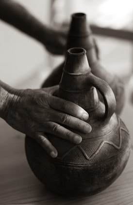 Close-up of hands gently holding a small ceramic bowl repaired with gold lacquer.