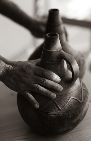 Close-up of a hand polishing a delicate antique ceramic vase with intricate floral patterns.