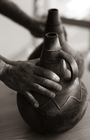 Close-up of hands arranging smooth terracotta pottery, highlighting craftsmanship and care.