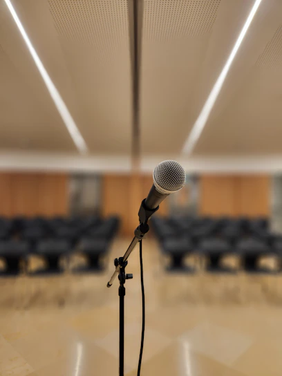 a microphone on a stand in front of a room full of chairs