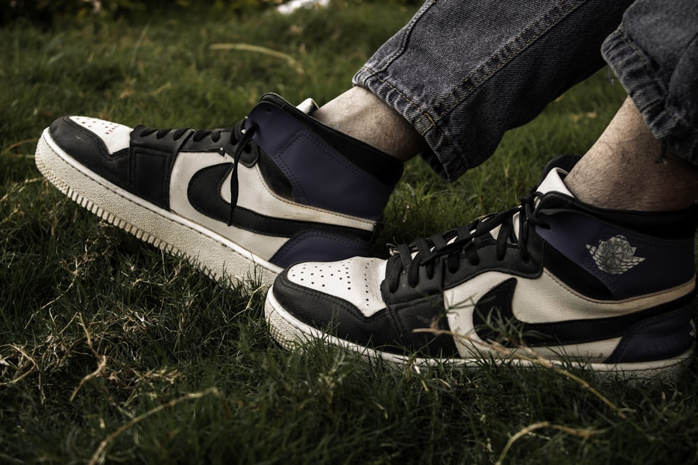 a pair of black and white sneakers sitting on top of a lush green field