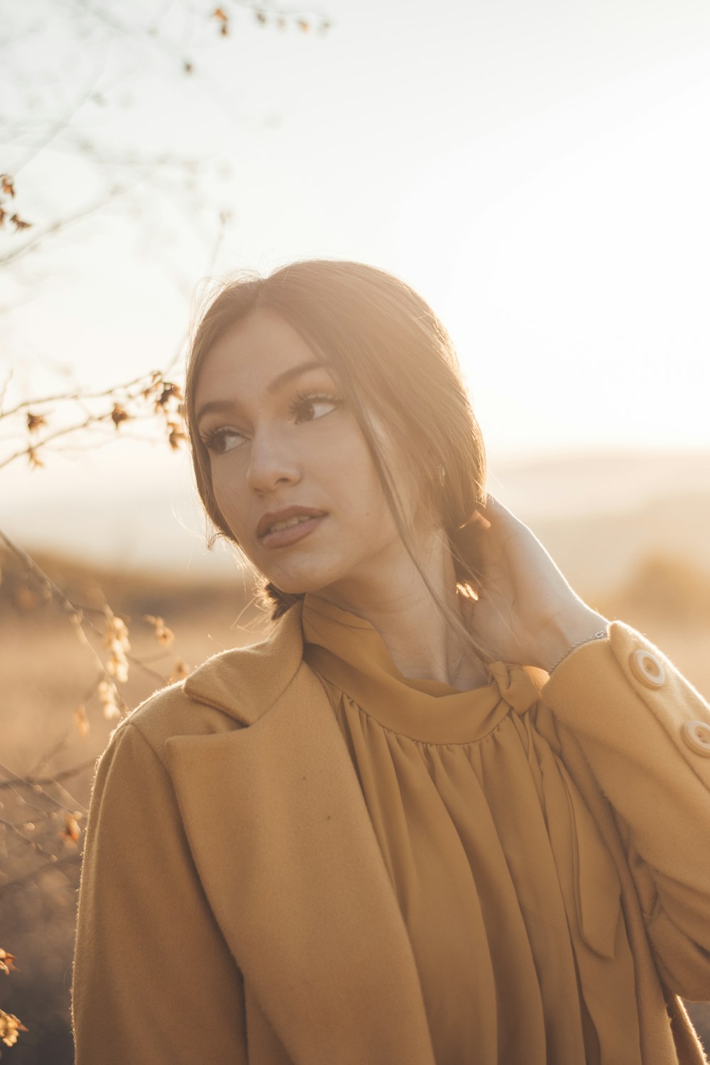 a woman standing in a field with her hand on her head