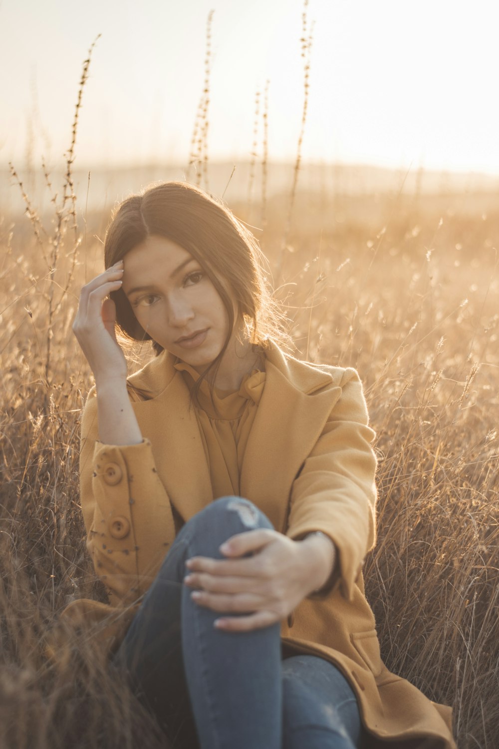 a woman sitting in a field of tall grass