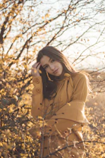 A cozy autumn scene with warm brown tones, featuring a person wearing natural makeup and layered earthy-toned clothing amidst falling leaves.