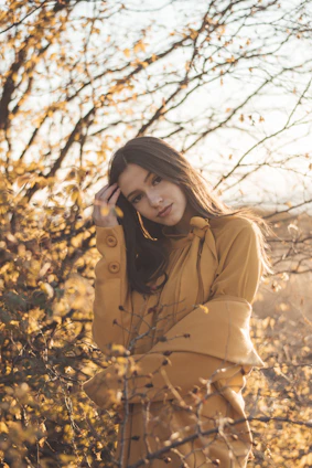 A cozy autumn scene with warm brown tones, featuring a person wearing natural makeup and layered earthy-toned clothing amidst falling leaves.