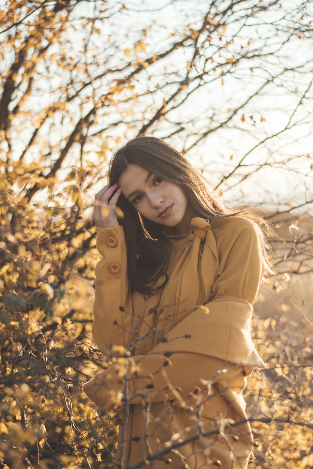 a woman standing in a field with a tree in the background