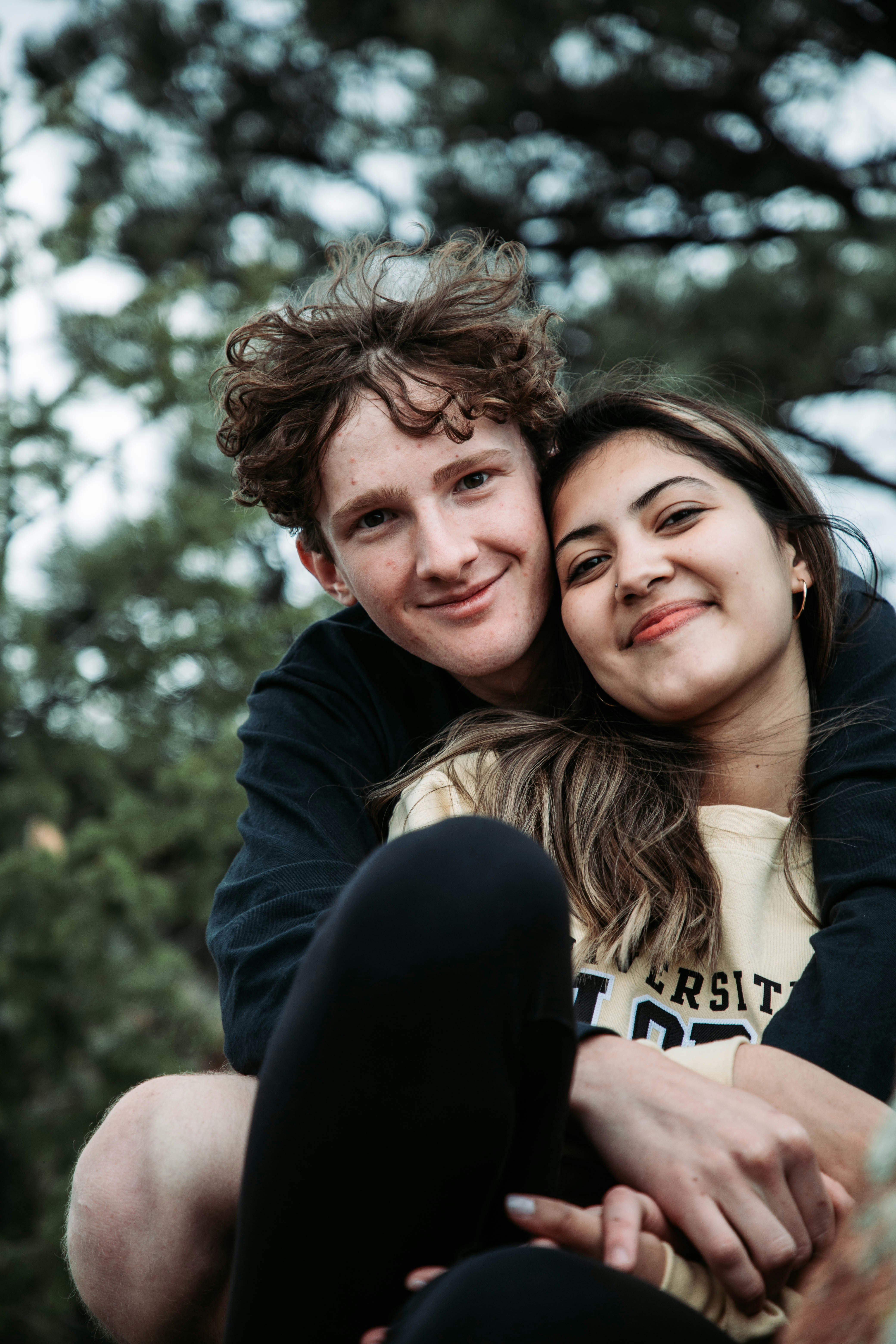 Couple smiling together outdoors in natural light with a green background