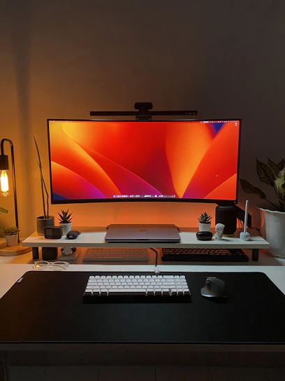 A modern desktop setup with a large monitor, keyboard, and mouse, styled with red and black accents.
