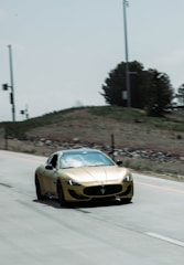 A sleek sports car gleaming under golden hour light on an open road.