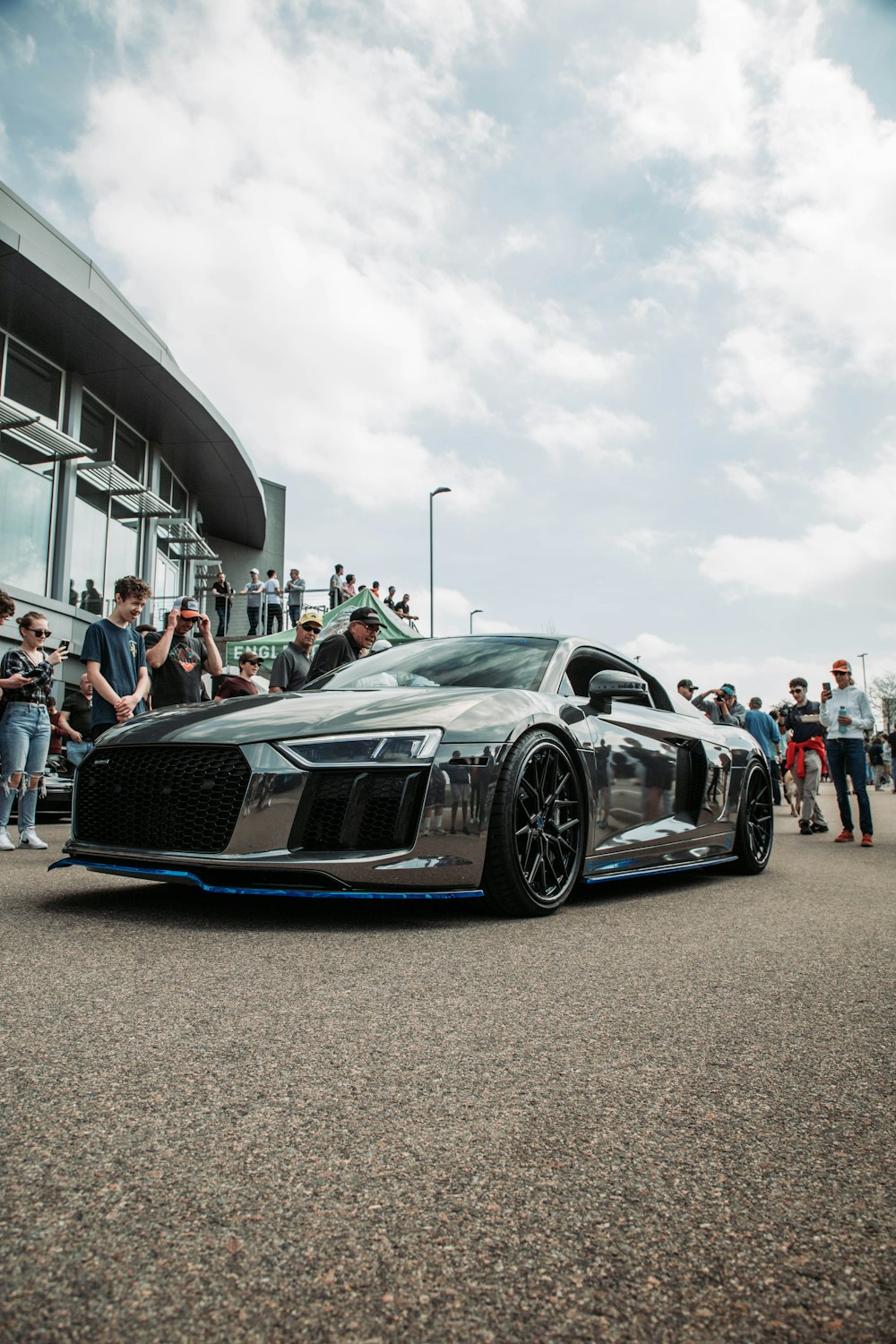 a silver car parked in front of a crowd of people