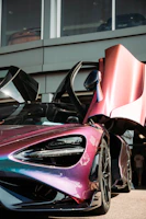 A sleek car gleaming with a glossy finish under pink and blue neon lights at Drift Wave.