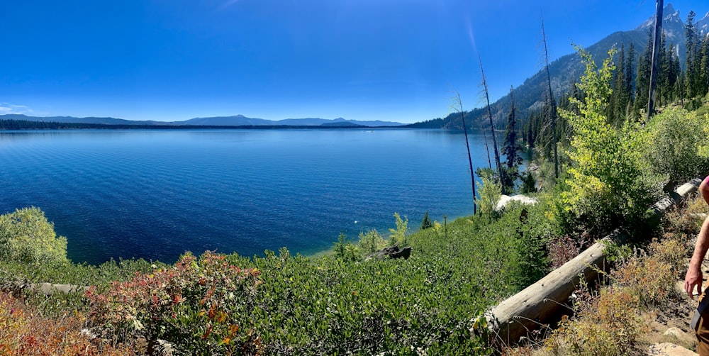 a man walking down a trail next to a large body of water