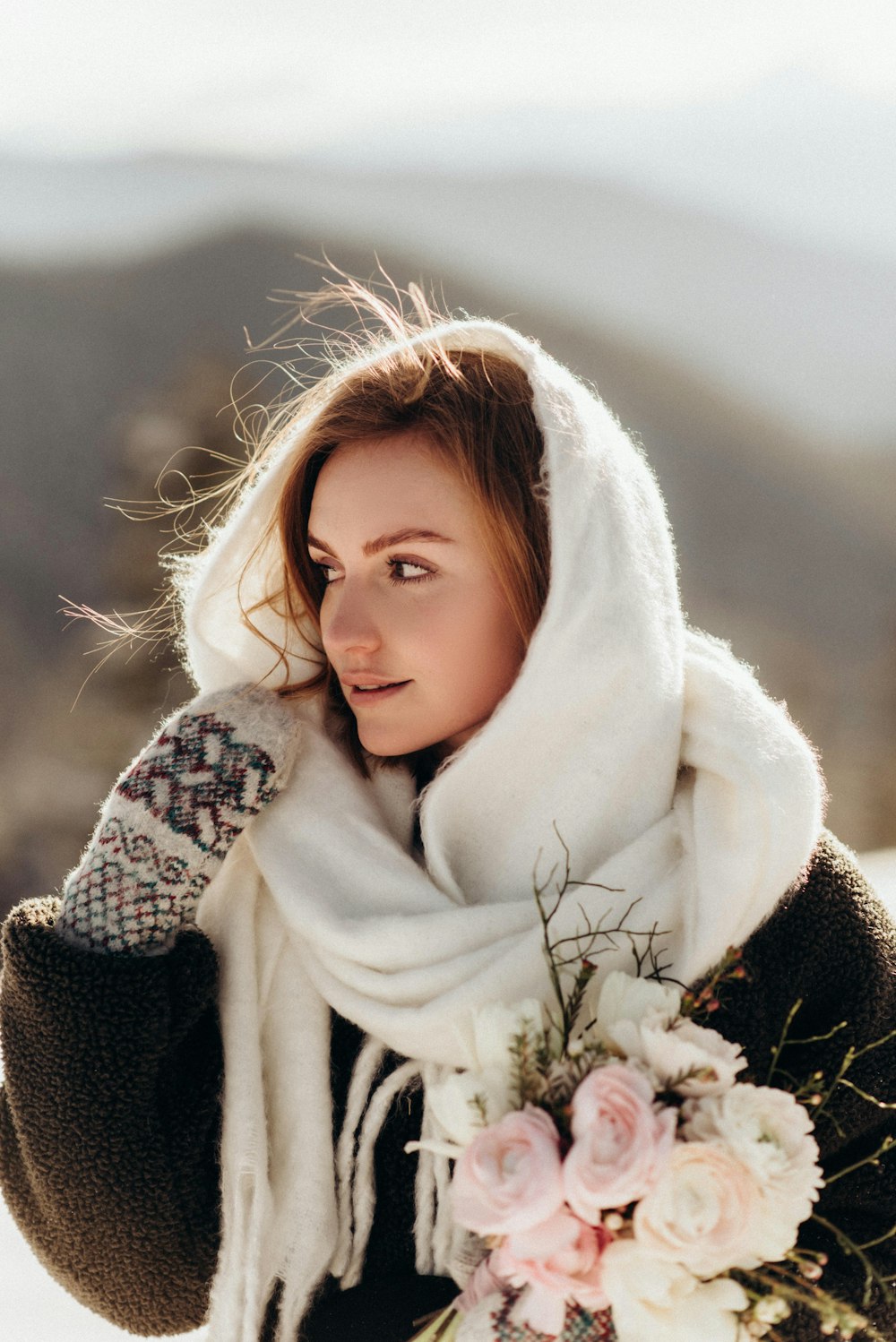 a woman wearing a scarf and holding a bouquet of flowers