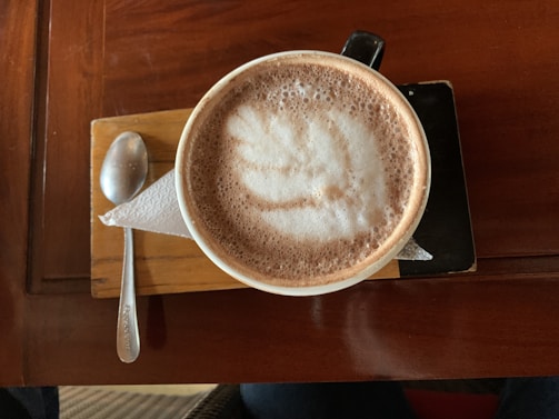 Close-up of a beautifully arranged coffee cup with latte art on a wooden tray.