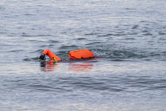A focused young swimmer practicing kicking techniques with a floatation aid.