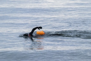 A swimmer wearing a streamlined wetsuit cutting through clear blue water.