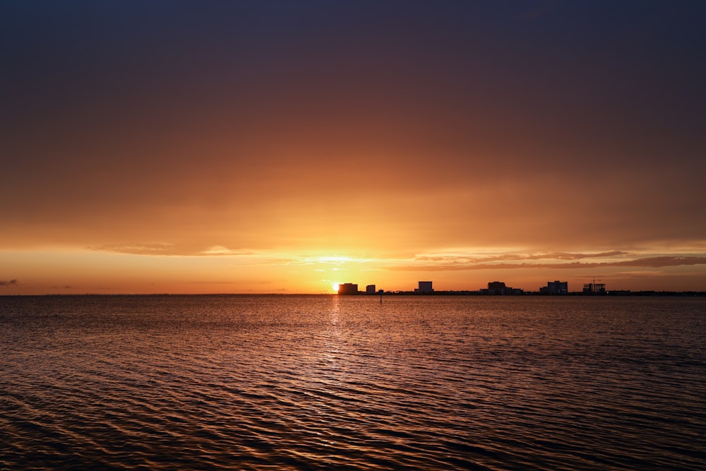 a large body of water with a sunset in the background