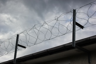 a barbwire fence with a cloudy sky in the background