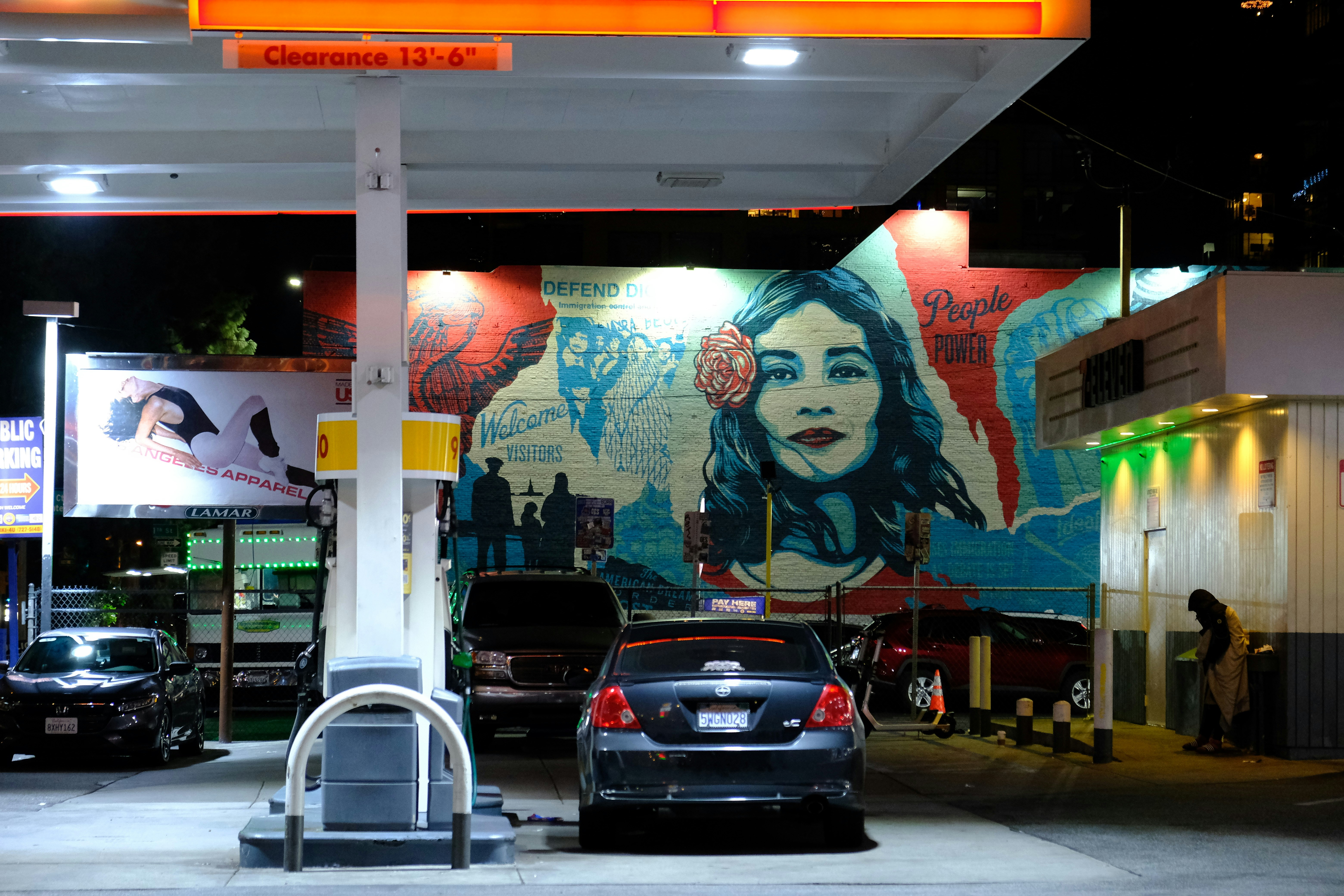 sebuah pompa bensin dengan mural seorang wanita di dinding
