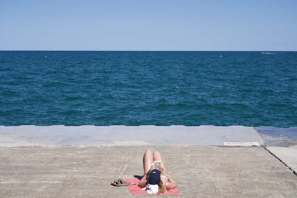 a person laying on a towel on a pier near the ocean