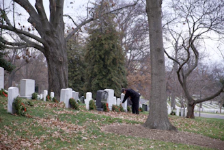 A respectful team member gently arranging seasonal flowers on a tombstone.