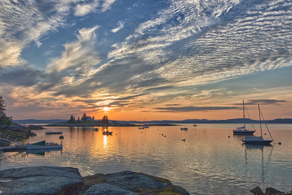 a beautiful sunset over a lake with boats in the water