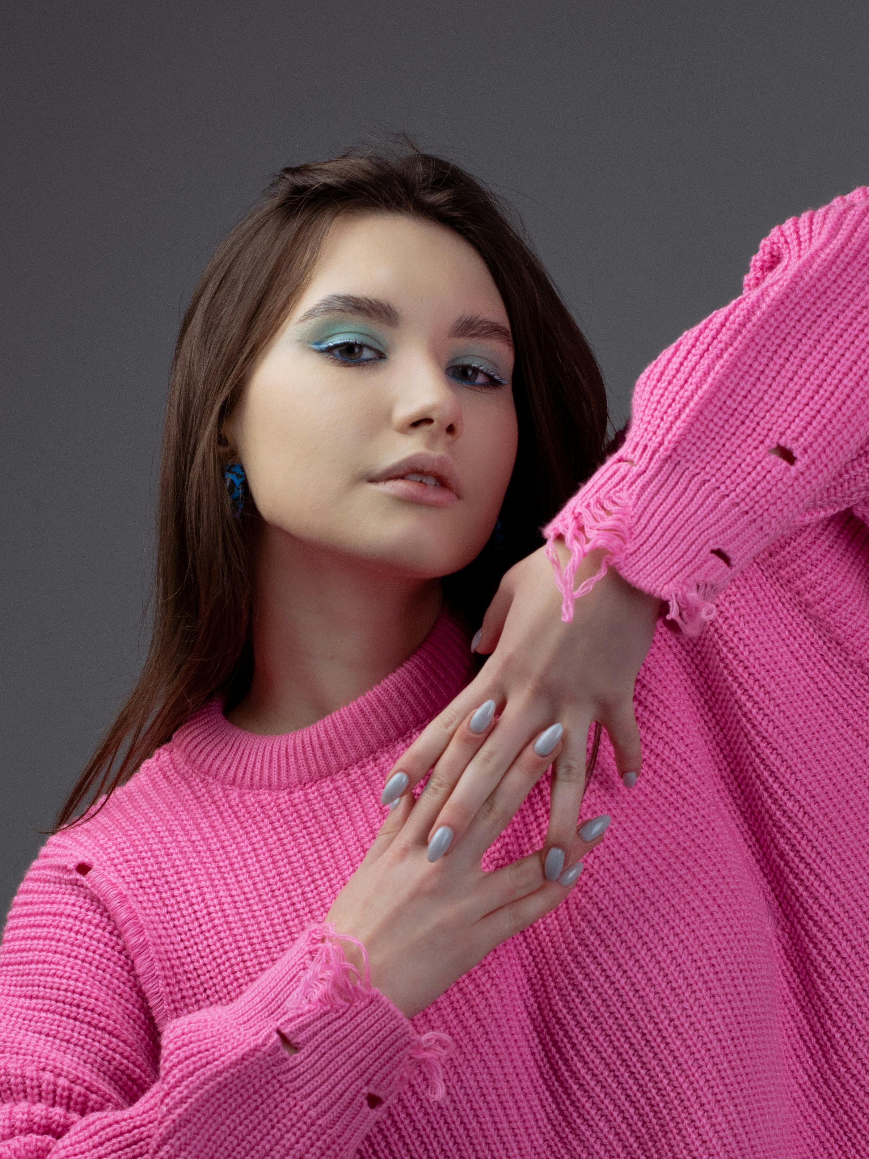 a woman in a pink sweater holding her hands on her shoulder