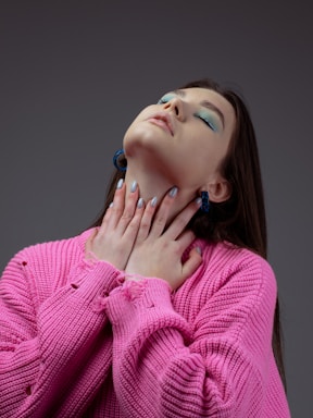a woman in a pink sweater with her hands on her chest