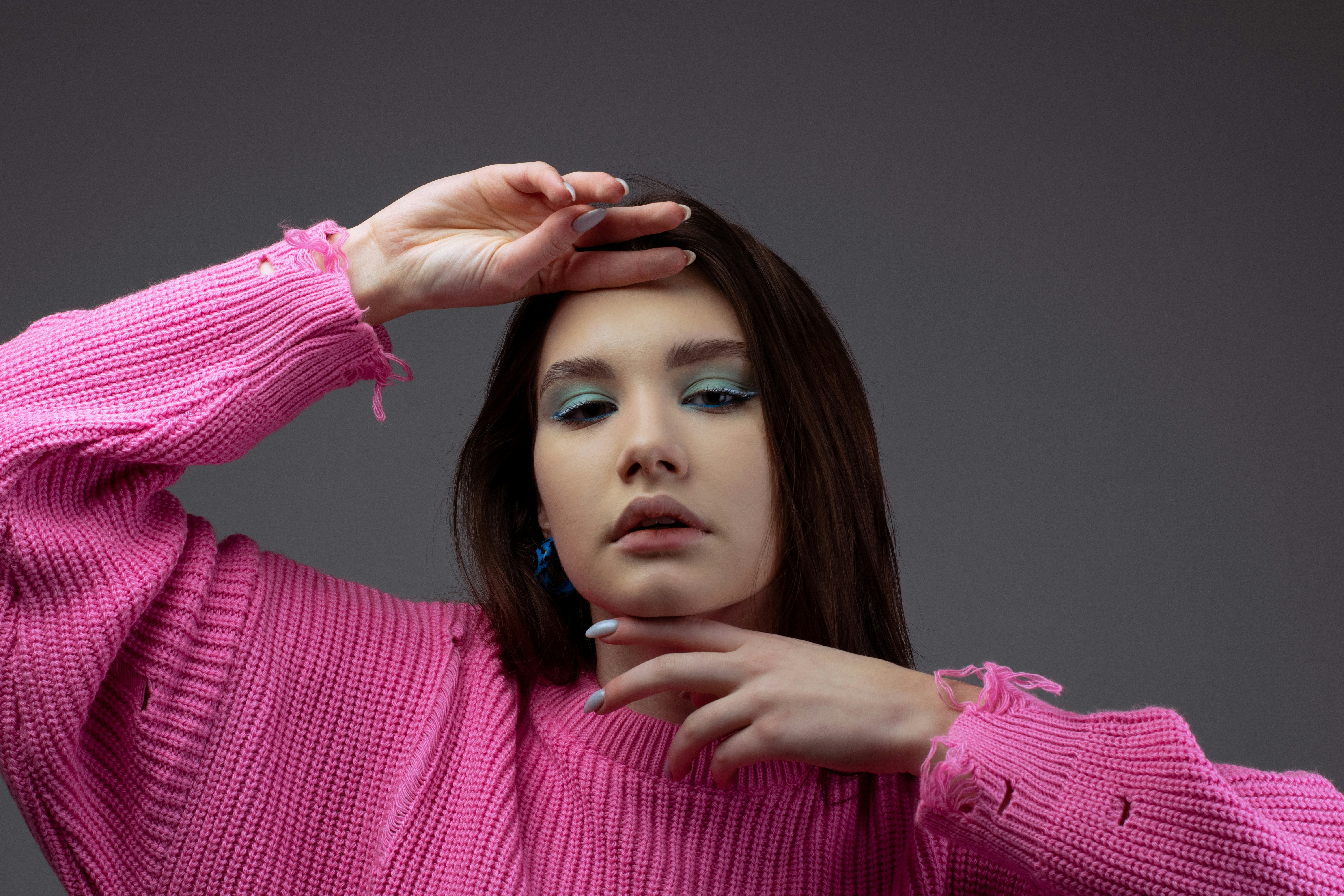 A woman in a pink sweater is holding her hands on her head