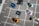 A collection of enamel pins arranged on a gray plaid fabric. The pins are designed to resemble cameras and software icons, including a blue rectangle with 'Ps' for Photoshop and a darker rectangle with 'Lr' for Lightroom. The camera pins come in various colors such as yellow, pink, and metallic hues.