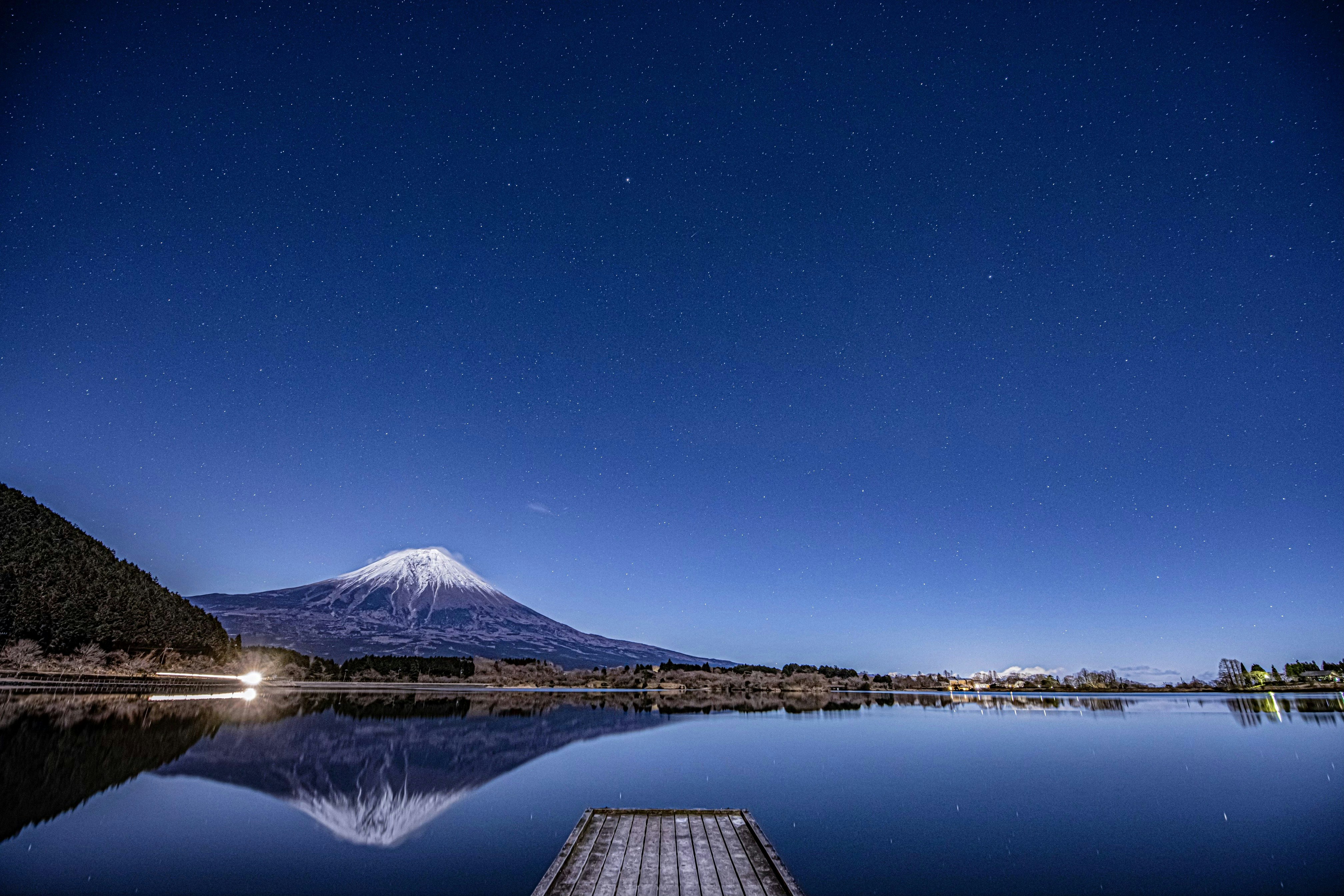 une vue nocturne d’un lac avec une montagne en arrière-plan