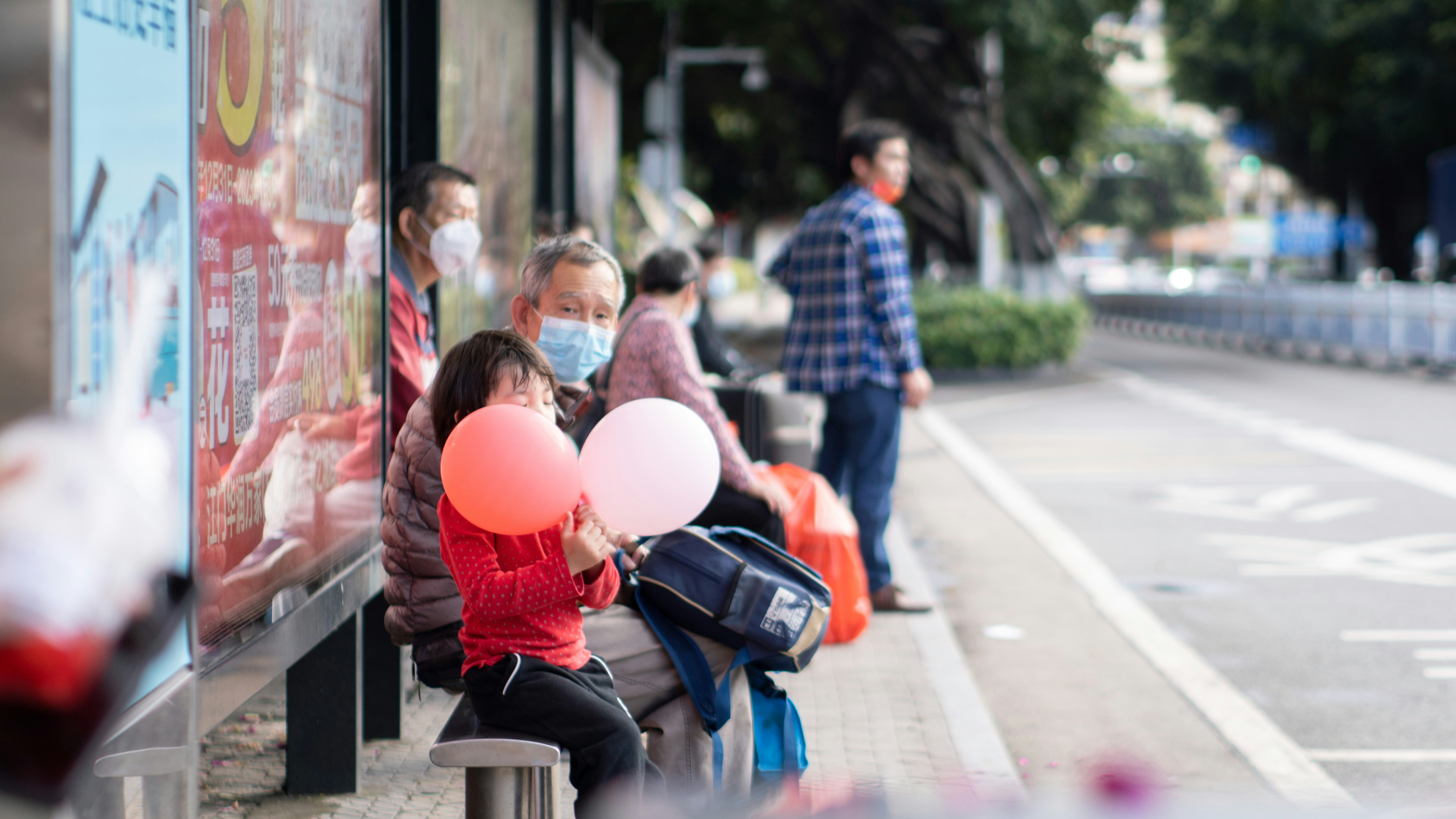 A group of people sitting on a bench with balloons