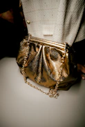 Chic crossbody bag with gold chain strap against a sleek black background