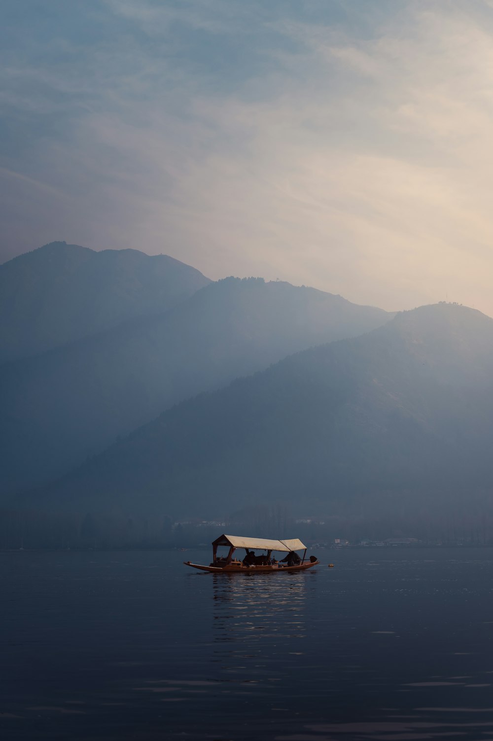 a boat floating on top of a lake under a cloudy sky