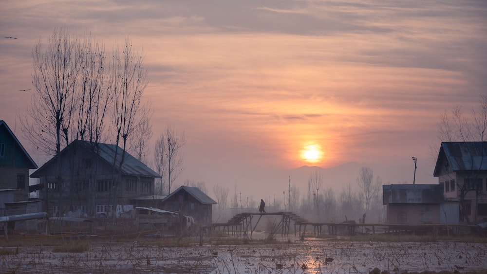 the sun is setting over a small village