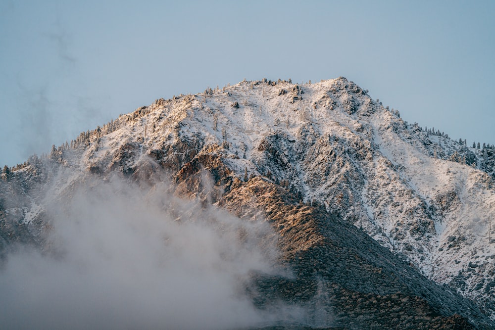 a mountain covered in snow with a cloud in the foreground