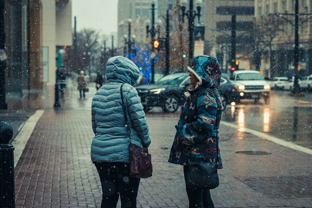 two women standing on a sidewalk in the rain
