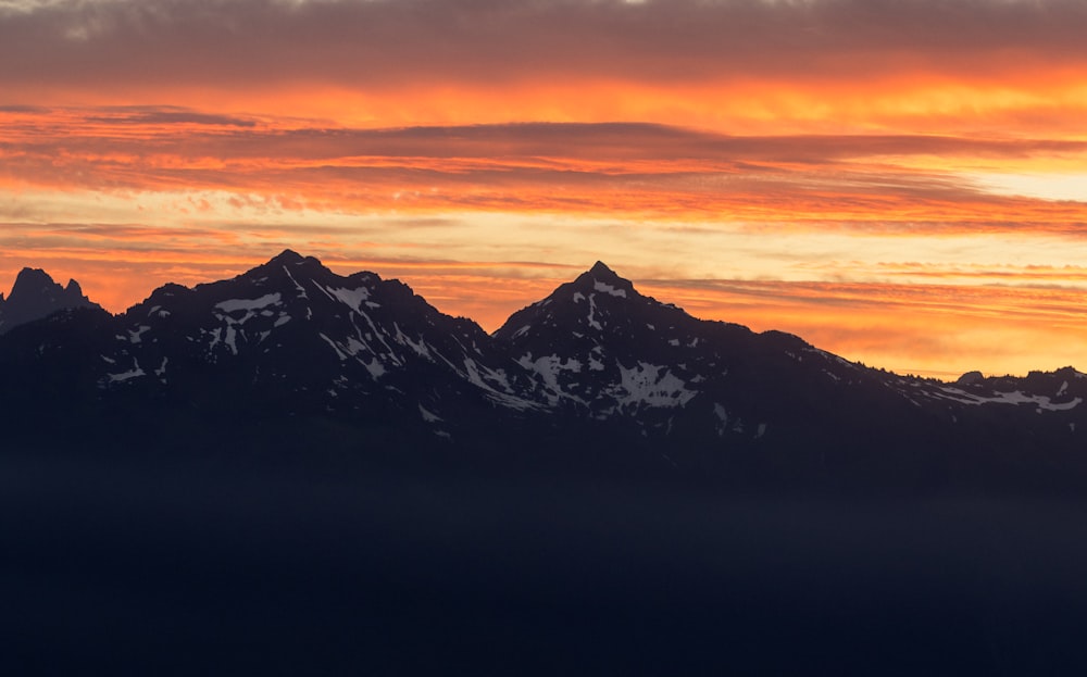 the sun is setting over the mountains in the distance