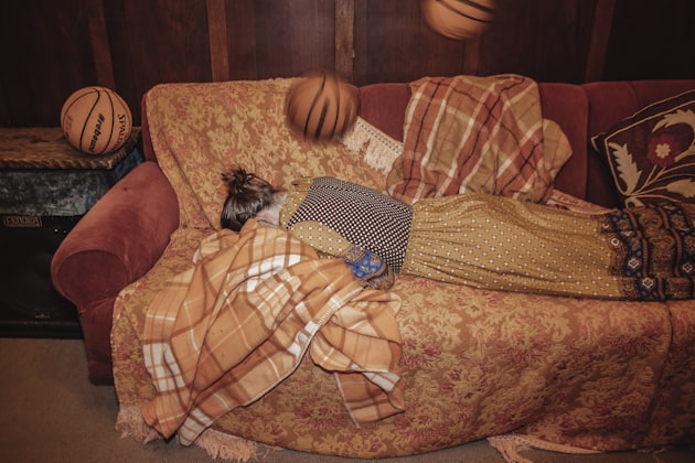 Personne confortablement installée sous une couverture sur un canapé
