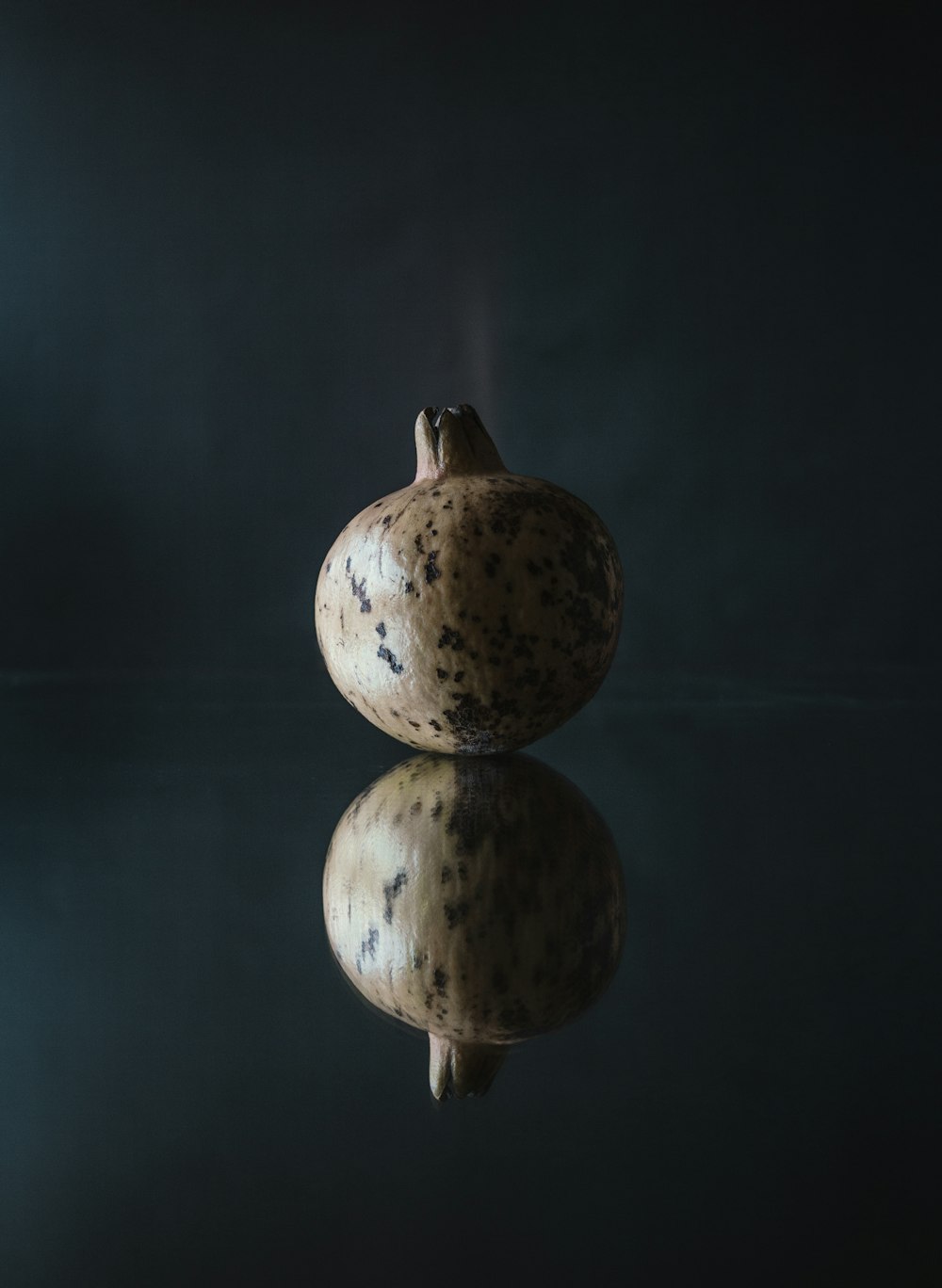 a pomegranate sitting on top of a reflective surface