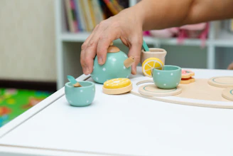 Close-up of a delicate 1:12 scale miniature tea set arranged on a tiny wooden table.