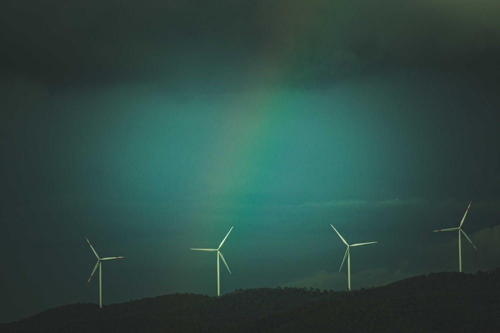 a group of windmills on a hill with a rainbow in the background