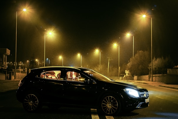 A sleek black sedan parked under soft yellow lighting at dusk