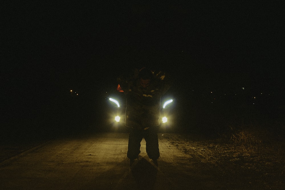 a man standing in the middle of a road at night