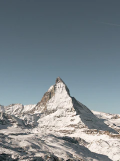 Snow-capped Mount Temple peak rising sharply against a crisp charcoal sky at dawn.