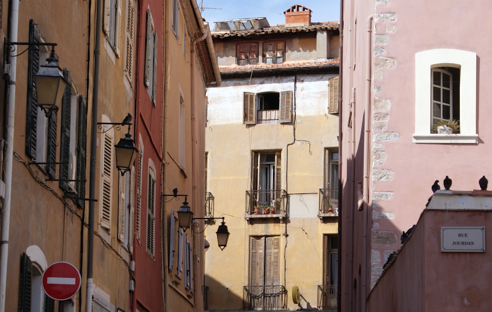 a narrow alleyway with several buildings and birds perched on the balconies