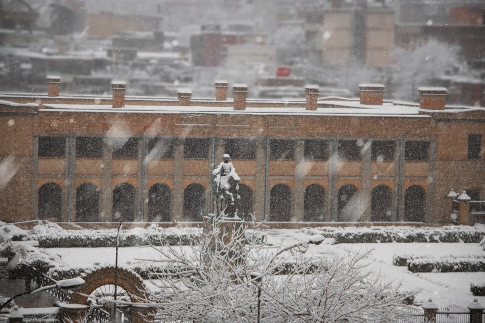 a snowy view of a building with a statue of a man on a horse