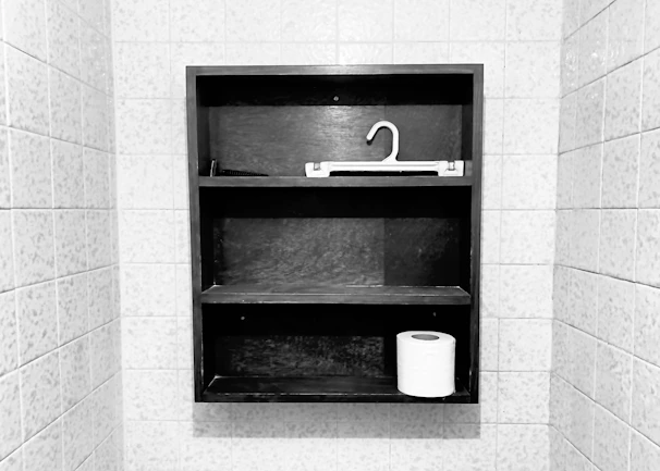A neatly arranged ceramic bathroom tissue holder set on a wooden shelf.