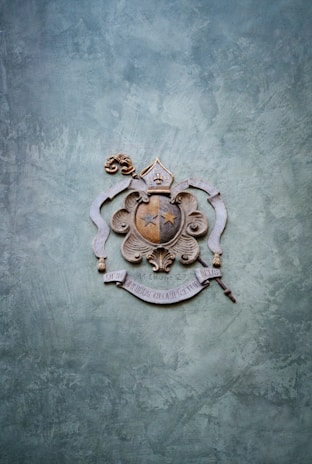 An ornate Victorian-style crest embossed in gold on a deep green velvet background.