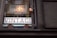 A vintage shop window displays a sign that reads 'Welcome Back to the 20th Century' with large, prominent letters spelling 'VINTAGE' beneath it. The sign is housed in a wooden frame, and the letters are illuminated against a textured wall.